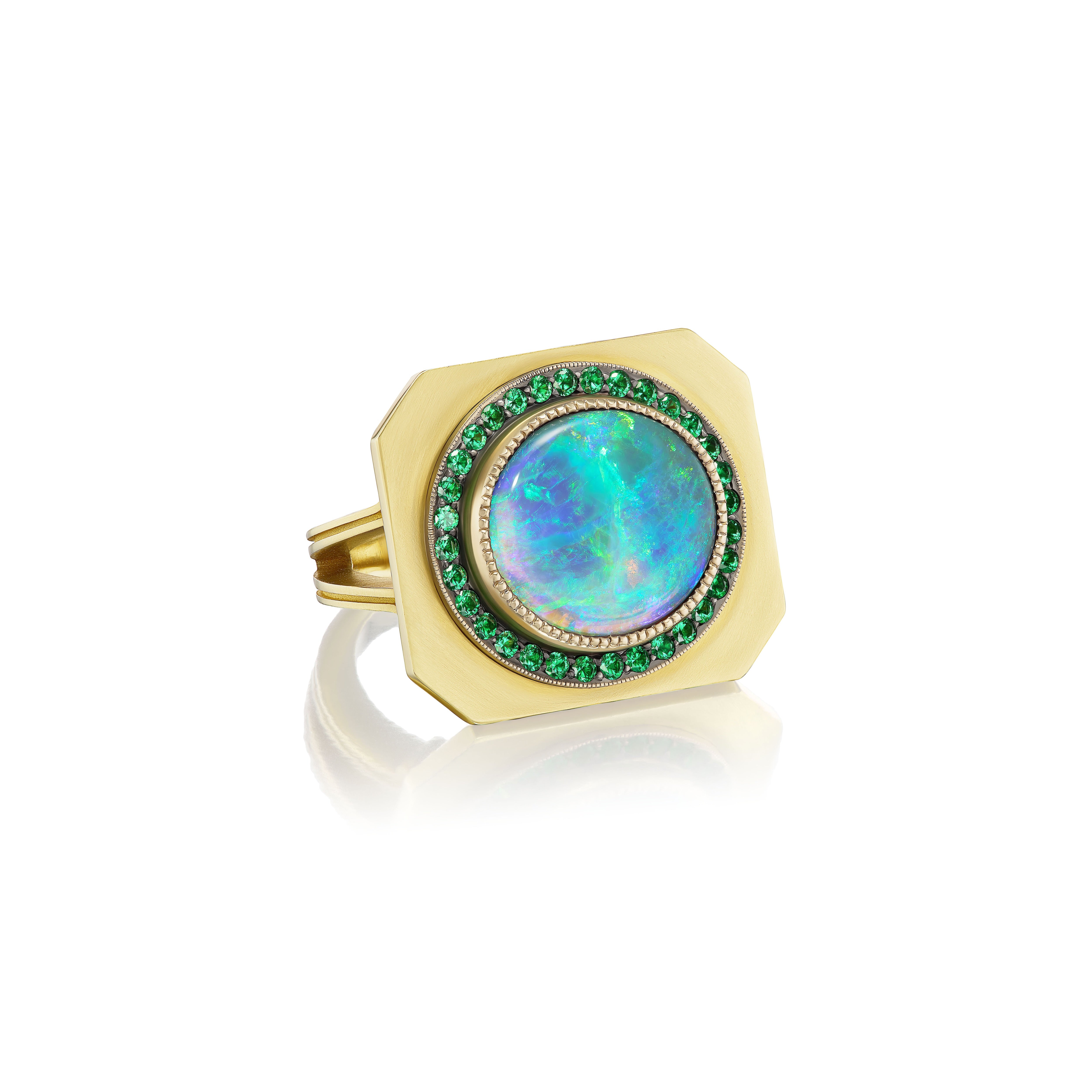 An 18k yellow gold signet-style ring featuring an oval Australian black opal surrounded by a halo of green tsavorites by Sylva & Cie