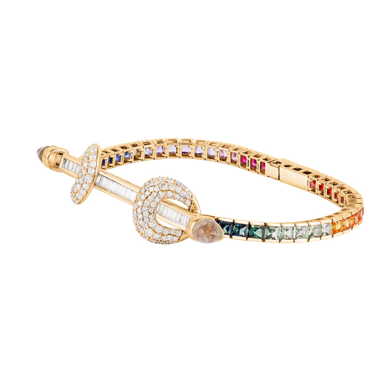 Ananya chakra bracelet with rainbow square cut multi colored sapphires. 18k yellow gold bar with baguette diamonds and diamond encrusted loops with cabochon crystals. 18k yellow gold ombre rainbow tennis bracelet